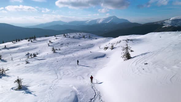Drone Following Couple of Hikers, Walking on Mountain Plateau in Winter