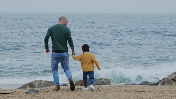 Father Is Walking With Son On Beach