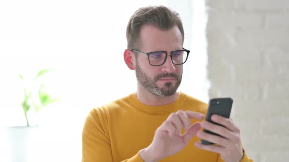 Portrait of Man Reacting to Loss on Smartphone alt