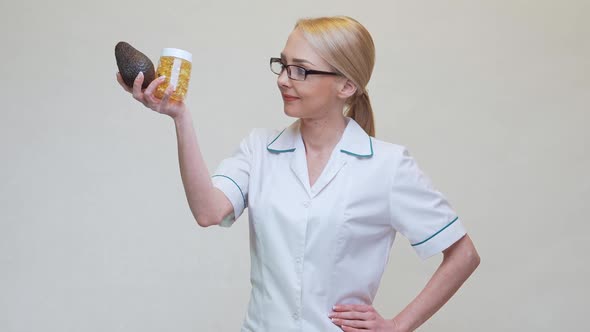 Nutritionist Doctor Holding Organic Avocado Fruit and Jar of Medicine or Vitamin or Omega 3 Capsules alt