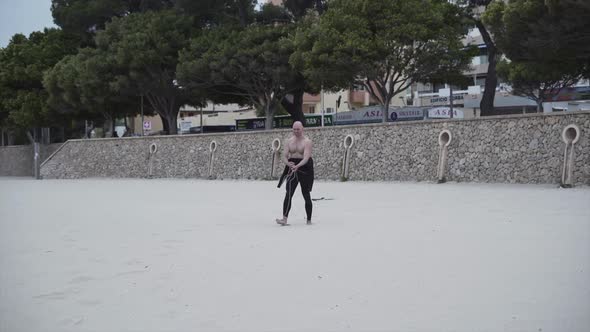 Shirtless Man Smiles At The Camera While Untangling Kite Lines At The Beach alt