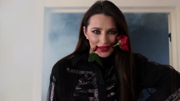 Beautiful Brunette with Stylish Makeup with Blood and Rose in Her Mouth alt