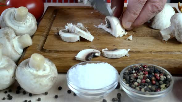 Chef Cutting Mushrooms with Large Sharp Kitchen Knife on Wooden Chopping Board alt