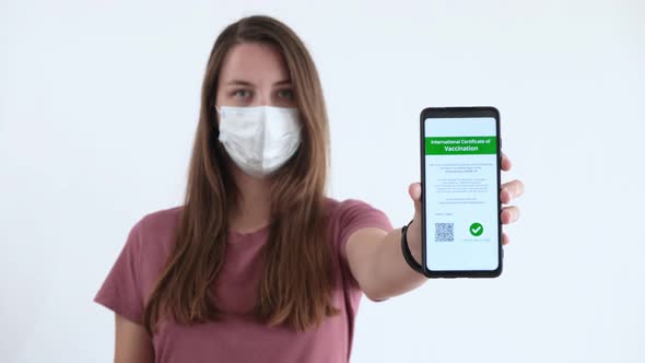 Woman in Face Mask Showing Certificate of Vaccination on a Mobile Phone
