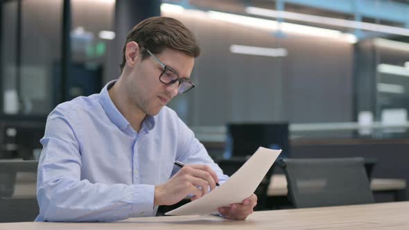 Young Man Reacting to Loss While Reading Documents alt