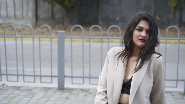Seductive Brunette with Tempting Makeup and in Stylish Clothes Posing Outdoors alt