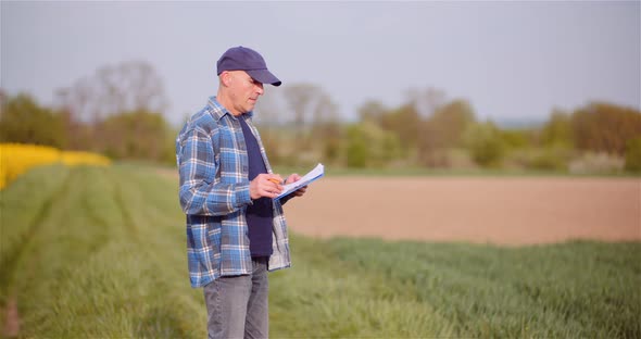 Thoughtful Male Botanist Writing On Clipboard. Farmer Examining Agriculture Field. alt