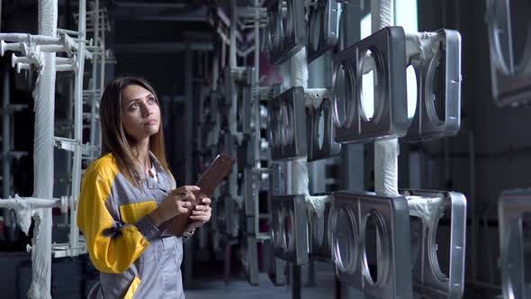 A Young Pretty White Woman Works in the Paint Shop of the Plant She Checks the Unpainted Metall alt