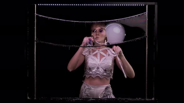 Young Girl Does Tricks with Soap Bubbles She Blows a Pipe with Bubbles of Smoke in Turn alt