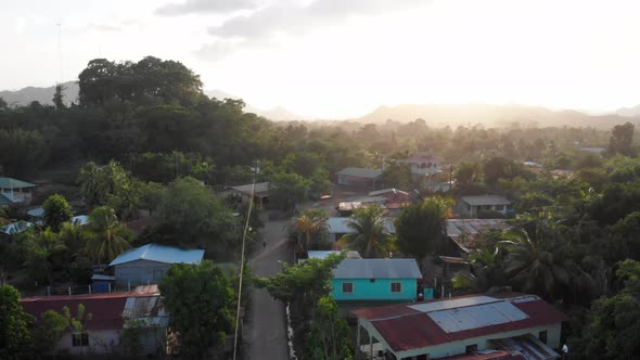 A drone shot of the late afternoon sun shining over a small Central American village alt
