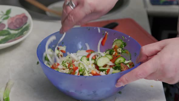 White Senior Woman Stirring Vegetable Salad in Blue Bowl with Fork Closeup View on Hands