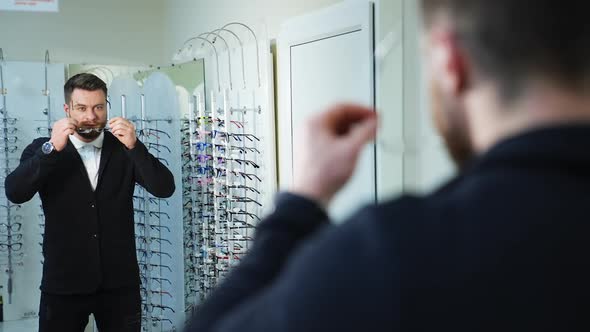 Portrait of fashion model man in modern casual outfit holds sunglasses standing in optics.  alt