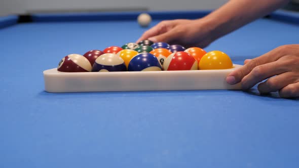 A man's hand strikes the white ball in an American billiard. Close-up of slow motion
