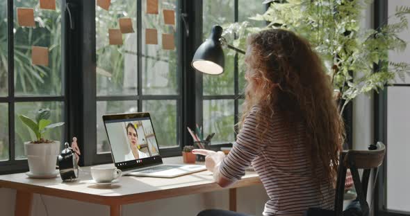 Young Caucasian woman chatting with female colleague online via video call