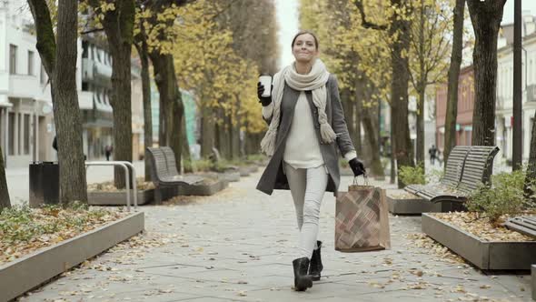 Happy Woman Walking With Shopping Bags And Coffee