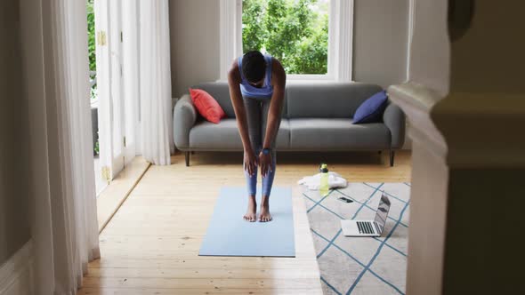 African american woman performing stretching exercise at home alt