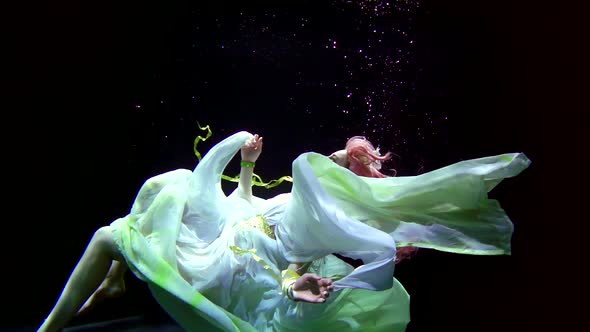 Woman Is Plunging in Depth of Large Aquarium, She Is Wearing Dress, Looking Up alt