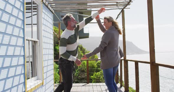 Happy caucasian mature couple dancing on the terrace by the sea alt