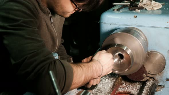 Turner Grinds the Metal Part Fixed on the Lathe with Sandpaper alt