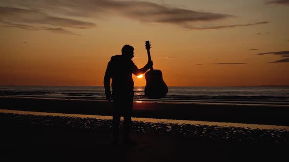 Man running with guitar in back sand beach at sunset. Beautiful, moody shots from the Sony a7iii. alt