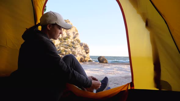 Woman Is Puts Her Shoes While Sits in Camping Tent at Beautiful Beach