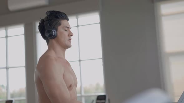 Athlete man listening to music and walking in treadmill