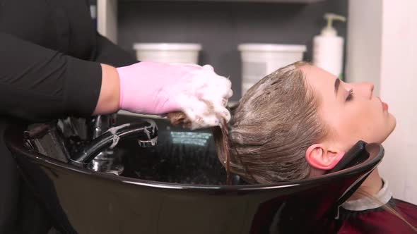 The Hairdresser Foams Shampoo on the Wet Hair of the Client in the Washbasin