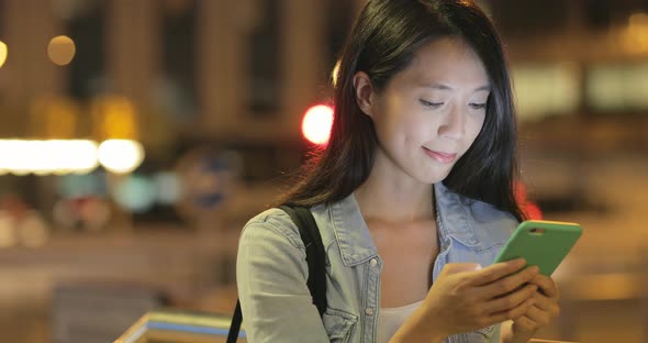 Woman watching on cellphone at night alt