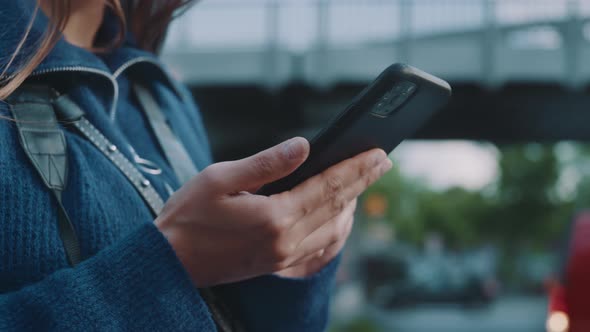 Young woman looks around and at her phone close up alt
