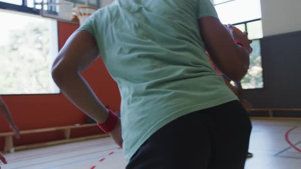 Diverse male basketball team and coach playing match alt