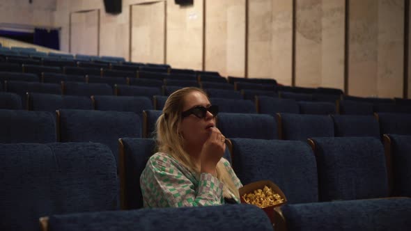 Young Alone Girl with Long Hair Eating Popcorn in Movie Theater
