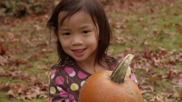 Young girl in Fall holding pumpkin