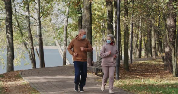 Wellness, Adult Couple Running Around a Forest Park, Autumn Day, Gray-haired Man and Woman Plays alt