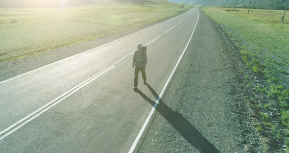 Flight Over Hitchhiker Tourist Walking on Asphalt Road alt