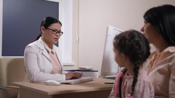 Family Doctor Making Medical Report on Computer alt