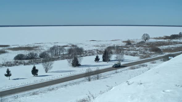 Aerial Top View From Drone of Vehicle Driving on Snowy Ice Road