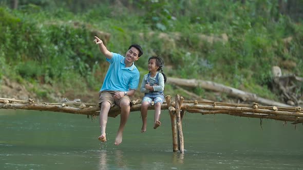 Father And His Daughter Sitting And Enjoying On Wooden Bridge alt