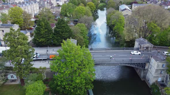 Aerial following traffic at speed as it filters across an old bridge in the English city of Bath alt