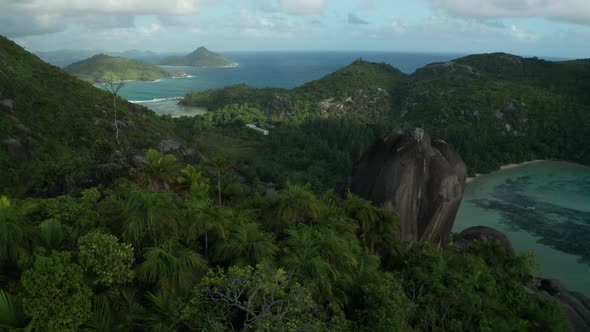 Aerial slider over top of mountain overlooking the bay and beach, Mahe alt