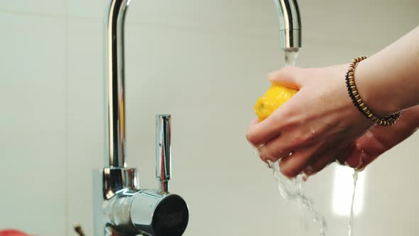 Woman's Hands Wash a Lemon Under the Tap with Water alt