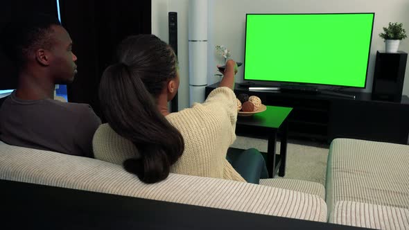 Young Black Couple Watch Television in Living Room and They Tussle for Control alt