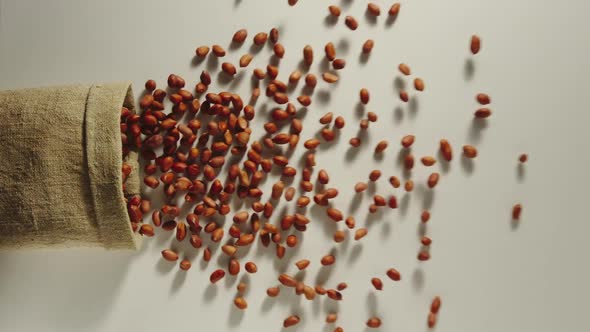 Bag Falls And Peeled Peanuts Are Poured Out Of It On White Background alt