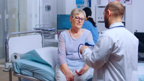 Practitioner Measures Senior Retired Woman Blood Pressure alt