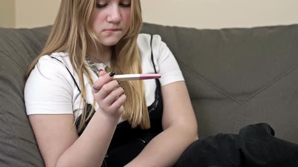 Portrait of Worried Teenage Girl Sitting on the Sofa While Holding a Pregnancy Test