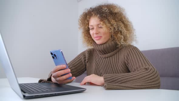 Happy young female using modern smartphone at home. Freelancer woman communicating online in 4k alt