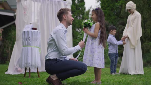 Side View Portrait of Caucasian Young Man Giving Wedding Bouquet to Charming Middle Eastern Flower alt