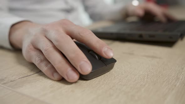 Caucasian male use wireless black mouse on wooden table for computer work alt