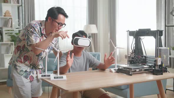 Asian Father Teach His Son While Wearing Vr Glasses With Electric Wind Turbine Model And 3D Printer alt