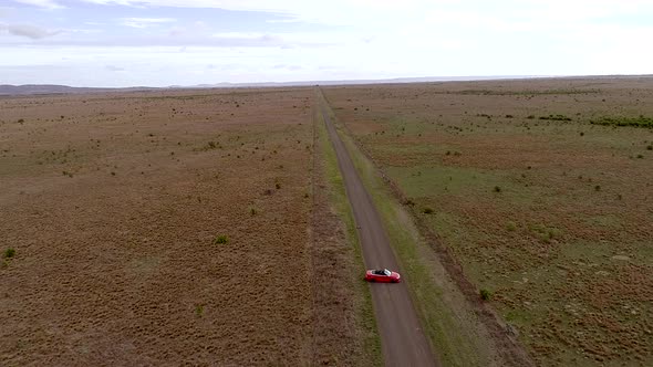 Aerial view of red car reverse and moving on country road