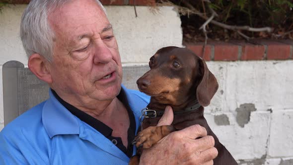 Senior cuddling a small dog alt